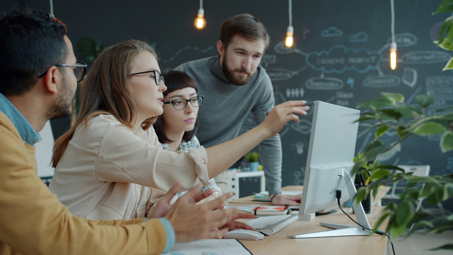 Team gathered around a laptop screen capturing process steps and documenting workflows in a modern office