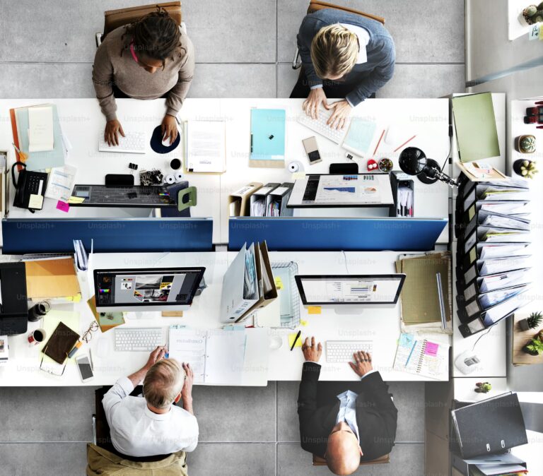 Top-down view of a leadership team reviewing dashboards and documents at adjoining workstations