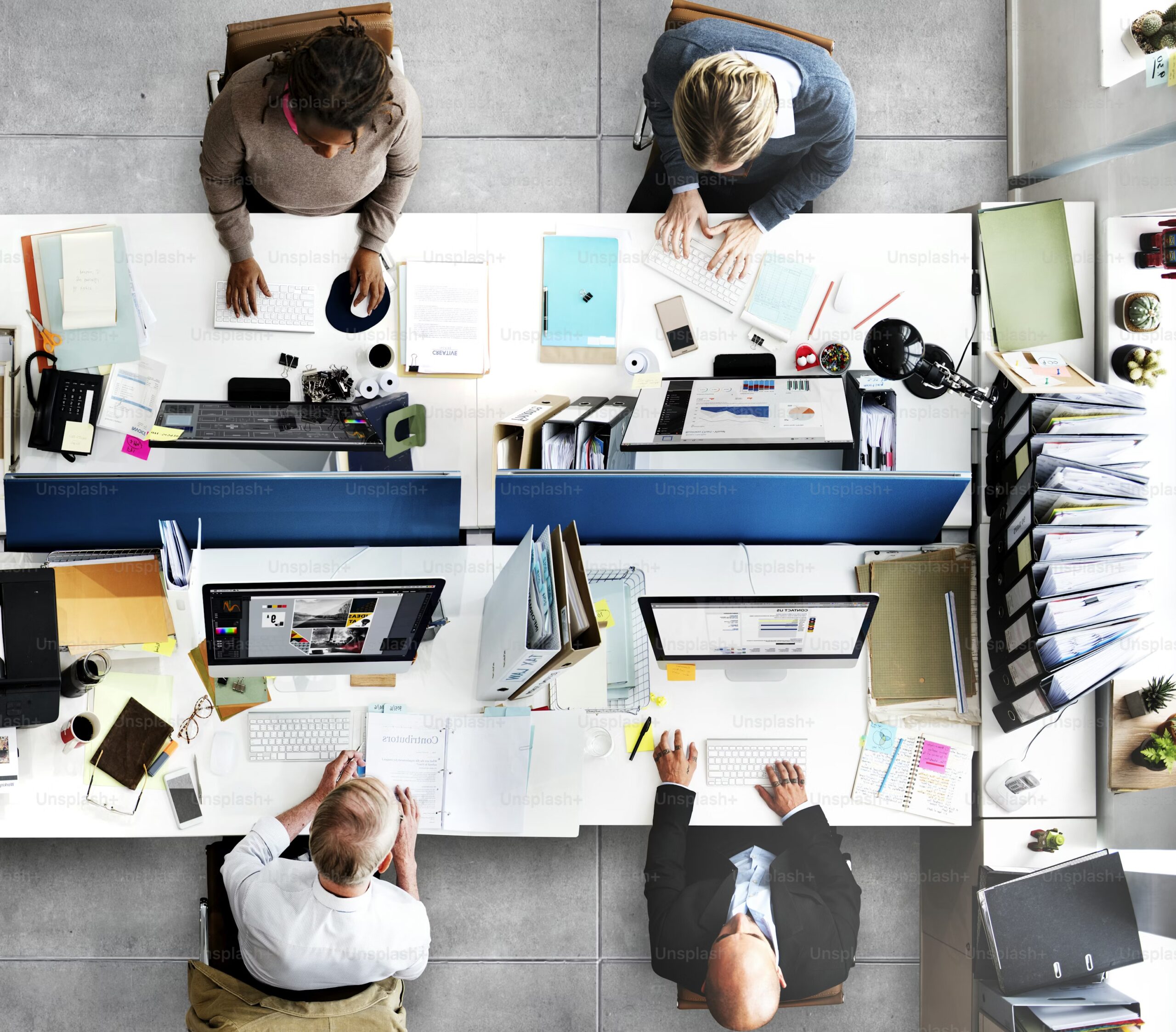 Top-down view of a leadership team reviewing dashboards and documents at adjoining workstations